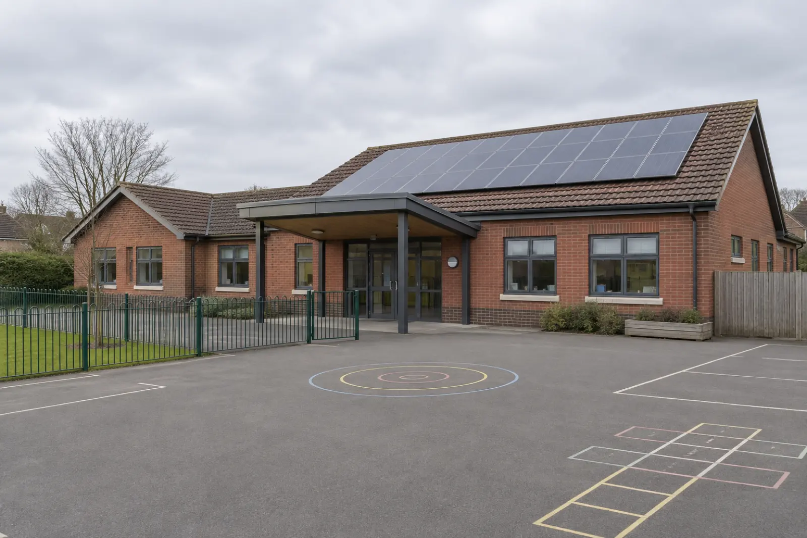 A single storey primary school in red brick, solar panels on the south facing slope of its pitched tiled roof