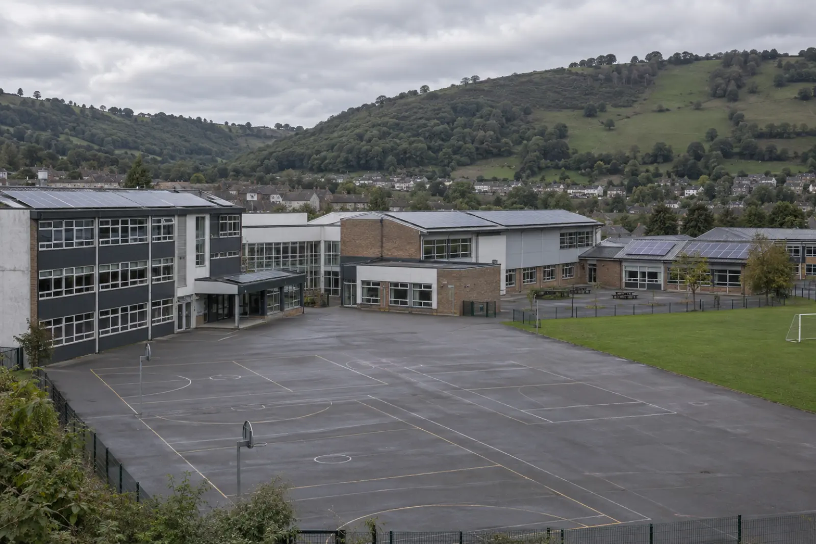 A school in a South Wales valley town, solar arrays on its roofs and steep green hillsides rising behind