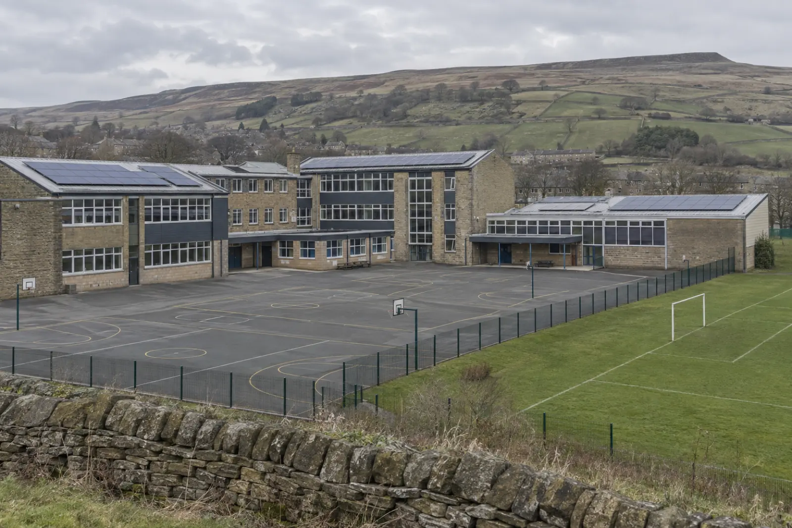 A school on the edge of a West Yorkshire town, solar arrays on its roofs and walled fields rising to moorland beyond